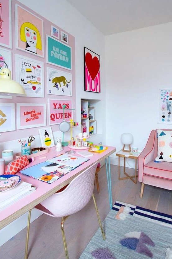 a pastel maximalist home office with a blush accent wall and a colorful gallery wall, a pink desk and a pink chair, a pink sofa and colorful textiles
