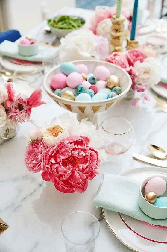 a pretty bright Easter table setting with bold blooms, colorful eggs in a bowl, mint napkins and pastel eggs in a cup