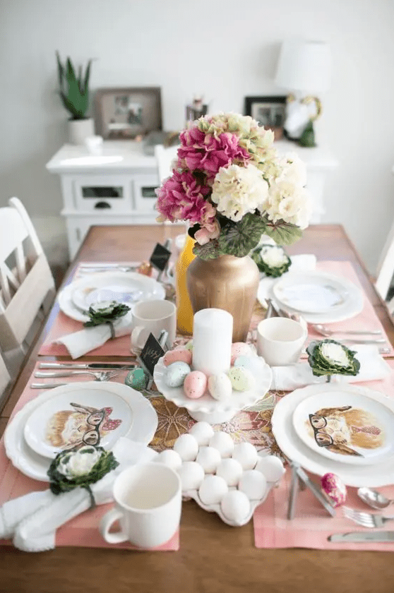 a pretty small Easter tablescape with pink placemats, a bold floral centerpiece, candles and pastel eggs plus bunny print plates