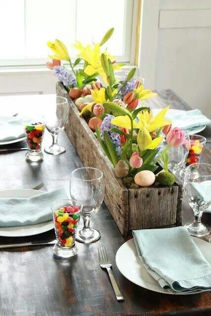 a pretty spring or Easter centerpiece of a wooden box with moss, pink, lilac and yellow blooms and leaves plus eggs