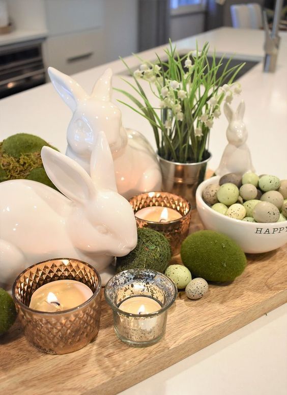 a rustic Easter centerpiece with moss and faux pastel eggs, bunnies, candles and some lily of the valley