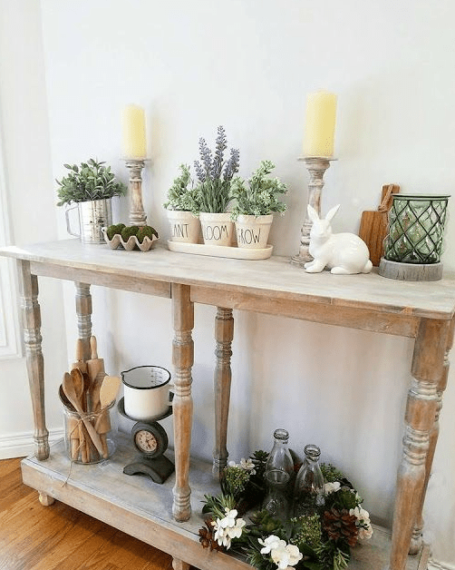a rustic Easter console table with potted greenery and flowers, moss, candles and a porcelain bunny
