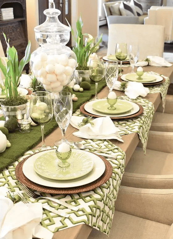 a rustic green and white Easter tablescape with printed napkins, woven placemats, moss, eggs, bunnies and greenery in tin cans