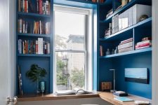 a small bright home office done in blue, with built-in bookshelves and a desk, a small window and a white chair is a cool idea for tight spaces