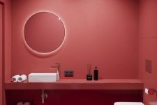 a sophisticated red minimalist powder room with matte walls, a floating vanity, a round lit up mirror, white appliances and ceiling lamps