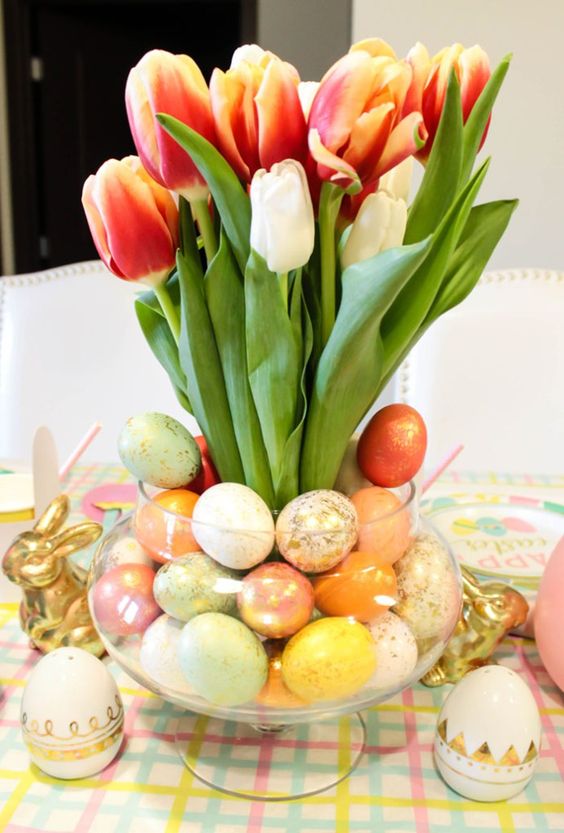 a spring centerpiece of a glass bowl with colorful faux eggs and orange and white tulips is a cool idea for Easter