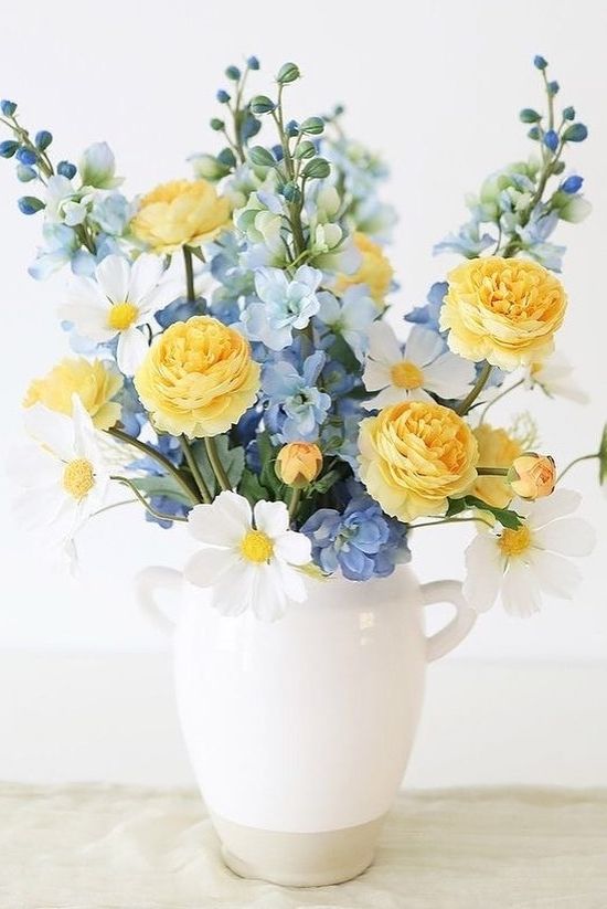 a spring floral centerpiece of blue, white and yellow blooms in a jug is a lovely idea for a spring tablescape in rustic style