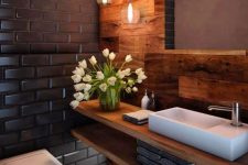 a stylish modern powder room with tiles, wood cladding the wall and floor, a floating vanity and a cluster of pendant lamps