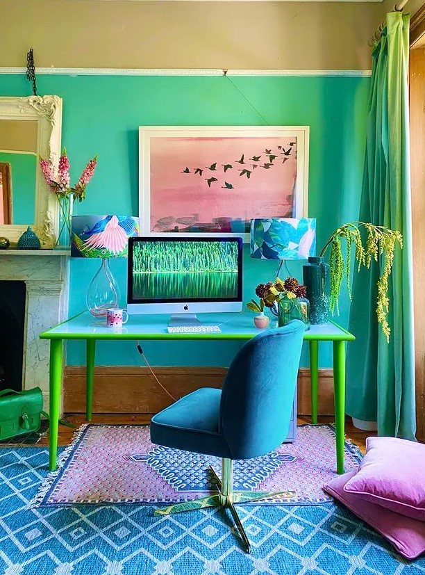 a vibrant maximalist home office with bold ombre walls, a blue and yellow desk, a bold blue chair, colorful almps, rugs and pillows