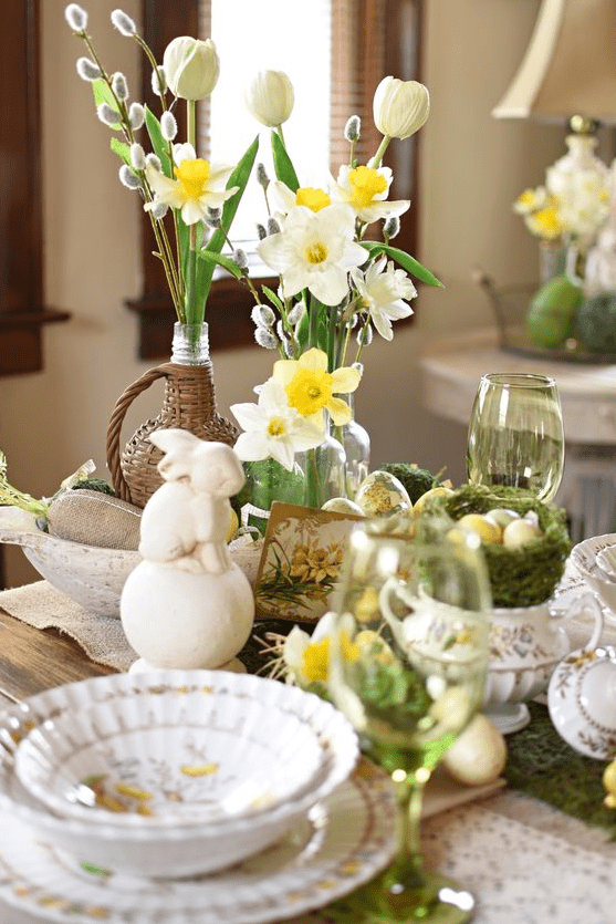 a vintage Easter centerpece of daffodils, tulips, willow, bunnies, moss and bowls and vases