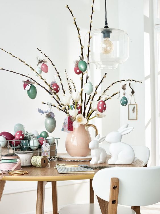 a whimsy Easter centerpiece of a blush jug with willow branches and colorful eggs is a super cool idea