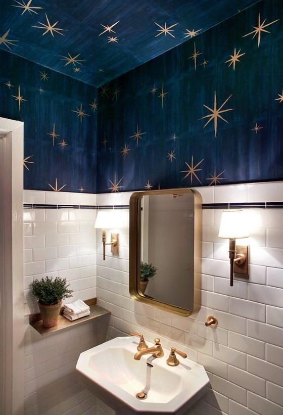 a whimsy powder room with white tiles, navy walls and a ceiling, gold stars, gold fixtures and a gold frame mirror