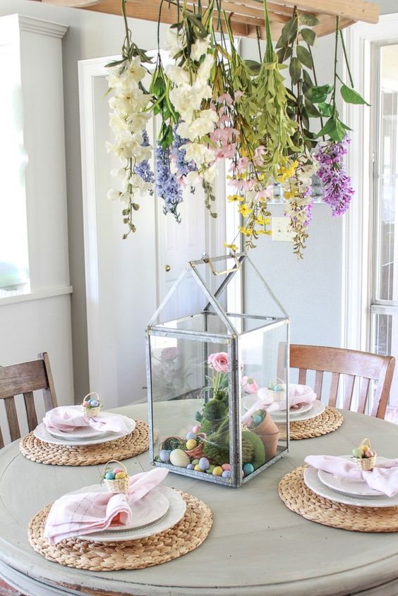 an Easter centerpiece of pastel and white blooms hanging over the table, a terrrarium with pink blooms, eggs and pots with moss