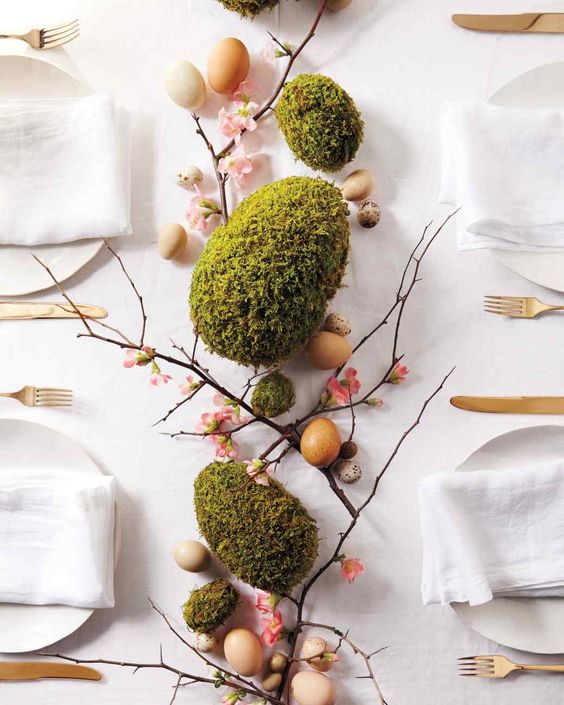 an Easter centerpiece of real and moss eggs and branches with blooms is a very creative and chic idea for any tablescape