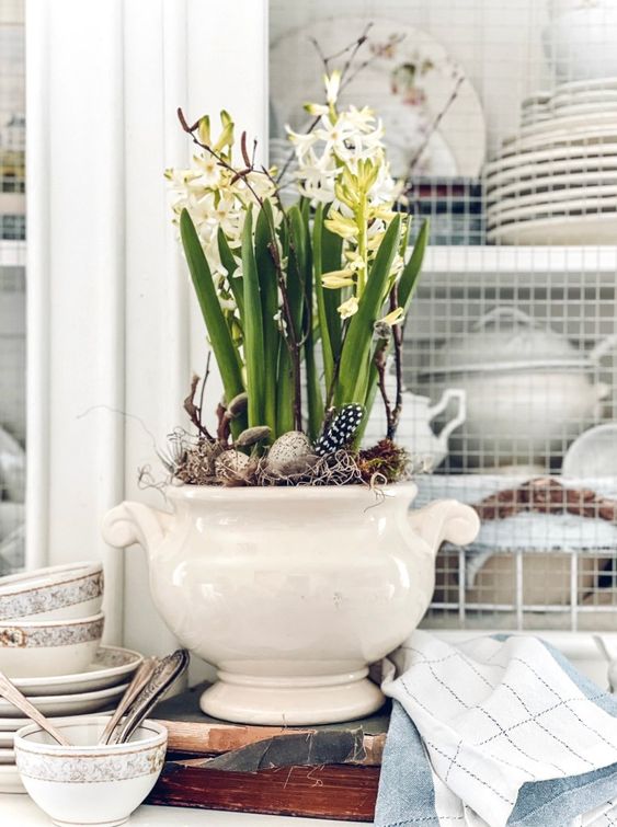 an Easter centerpiece with spring bulbs, twigs and feathers and speckled eggs is a lovely decoration