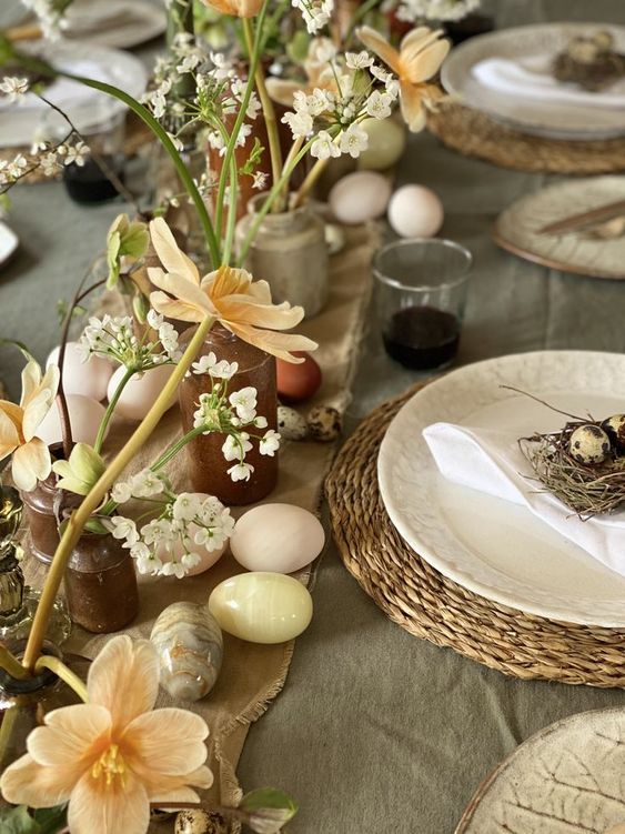 an organic Easter tablescape with textural linens, woven placemats, fresh blooms in clay vases and rock eggs plsus faux nests