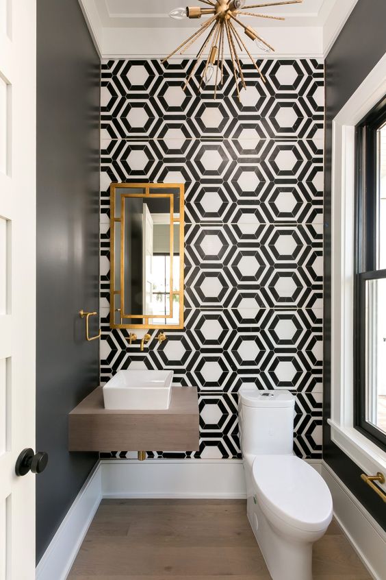 an ultra-modern and chic powder room with black and white hex tiles, a floating vanity, white appliances and a sunburst chandelier
