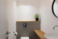 geometric tile wall accentuates the toilet zone and light-colored wood contrasts it perfectly