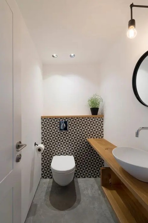 geometric tile wall accentuates the toilet zone and light colored wood contrasts it perfectly