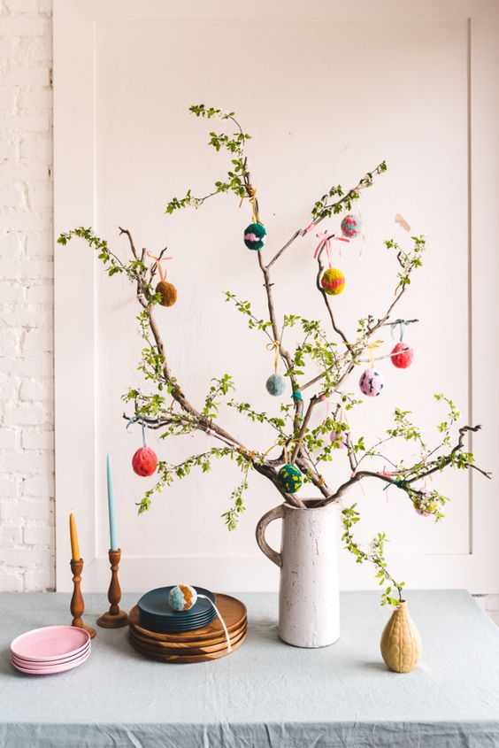 natural greenery branches with colorful pompoms instead of eggs are amazing to style your space for spring adn Easter
