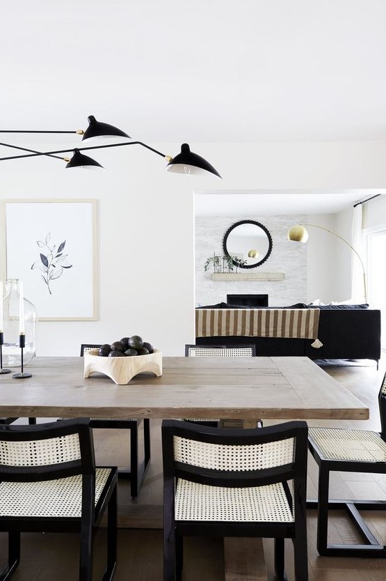 a breathtaking black and white dining room with a large stained table, neutral and black chairs, black lamps