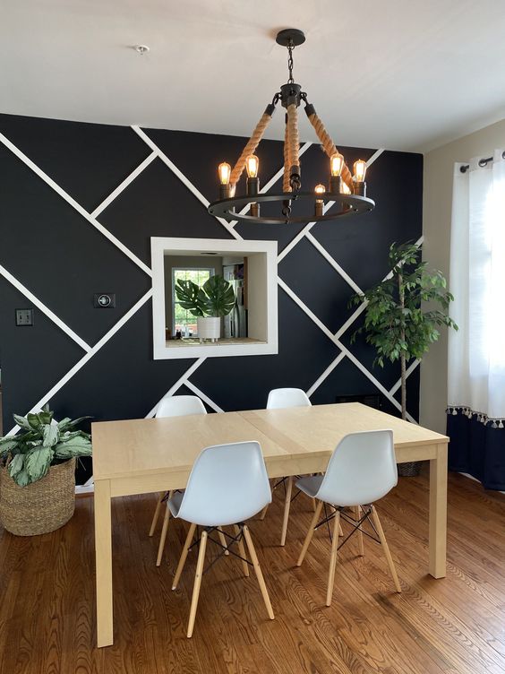 a catchy modern dining space with a graphic accent wall, a stained table and white Eames chairs, a unique chandelier and potted plants