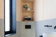 a contemporary guest toilet with a frosted glass window, penny tiles and plywood, with storage shelves and a wall-mounted sink
