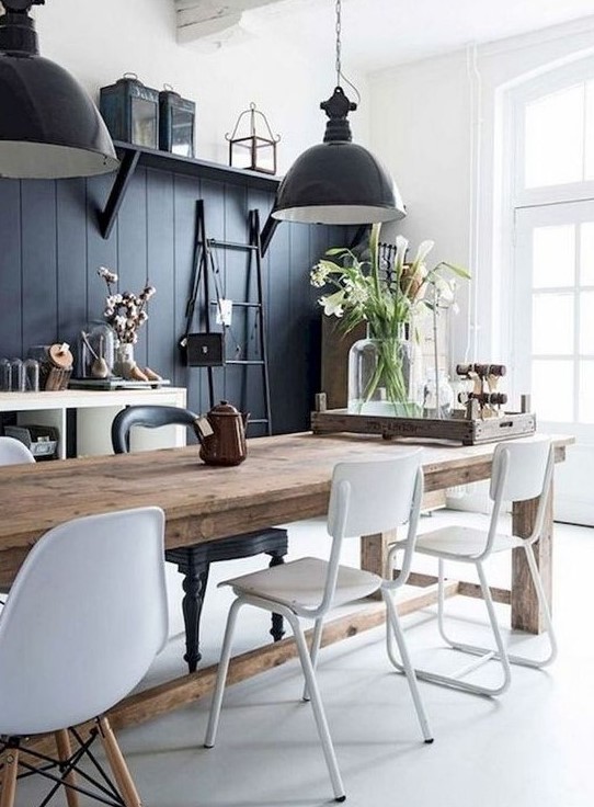 a contrasting monochromatic dining area with a black wall, a wooden table, white chairs, black pendant lamps