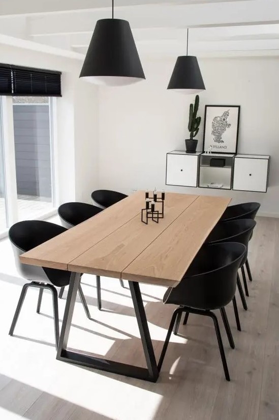 a laconic contemporary dining space with a wooden dining table, black chairs, black pendant lamps and a floating storage unit