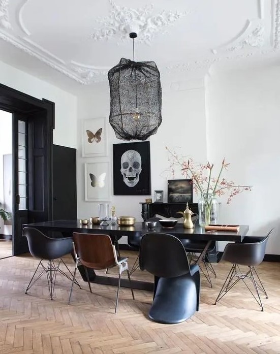 a modern Gothic dining room with white walls and a ceiling, black doors, a black table and chairs plus a pendant lamp