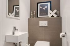 a neutral guest toilet done in taupe and white, an artwork, a wall-mounted sink and a large mirror