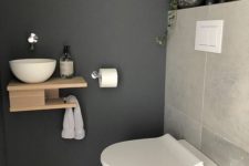 a tiny guest toilet with stone tiles, a wall-mounted wooden vanity with a vessel sink and a potted plant