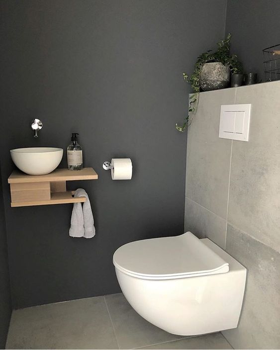 a tiny guest toilet with stone tiles, a wall mounted wooden vanity with a vessel sink and a potted plant a tiny guest toilet with stone tiles, a wall-mounted wooden vanity with a vessel sink and a potted plant