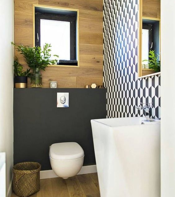 a tony guest toilet with a geometric wall, a free standing sink, a plywood and matte black wall plus a black framed window a tony guest toilet with a geometric wall, a free-standing sink, a plywood and matte black wall plus a black framed window