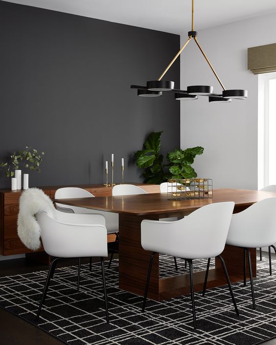 an elegant mid-century modern dining room with a black accent wall, a stained table and a credenza, white chairs and a graphic rug