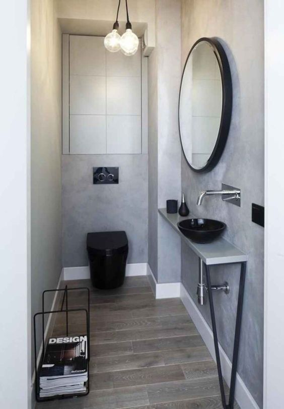an industrial guest toilet done with concrete, a sleek vanity with a metal leg, a blakc toilet and some bulbs an industrial guest toilet done with concrete, a sleek vanity with a metal leg, a blakc toilet and some bulbs