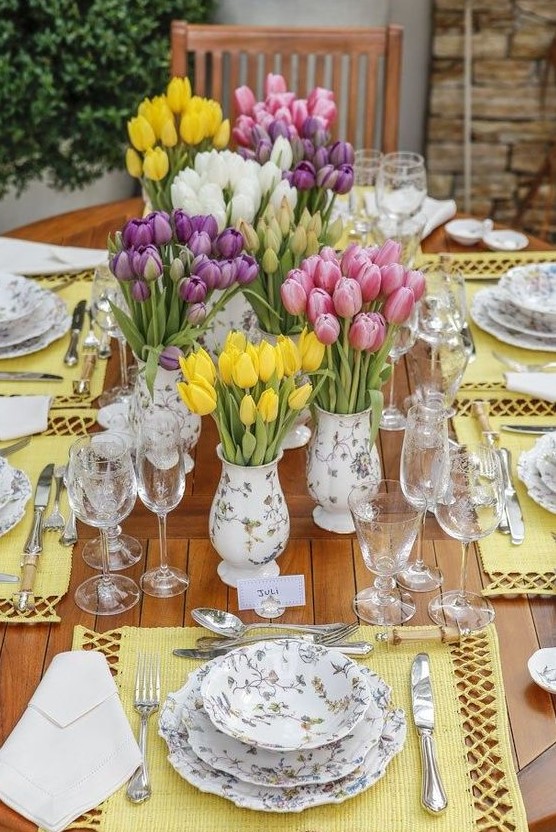 a colorful spring tablescape with bright yellow placemats, prited floral porcelain and lots of colorful tulips