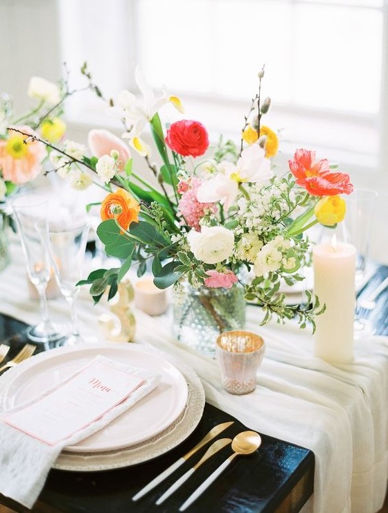 a neutral runner, a colorful floral centerpiece, candles, gilded cutlery and pastel plates for a vibrant look