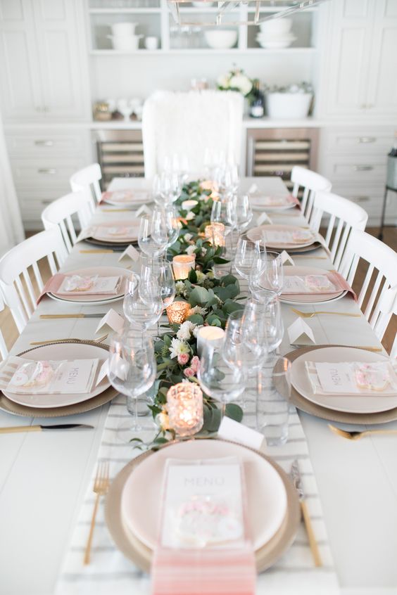 a pretty Mother's Day table setting with a printedrunner and napkins, a greenery and blush bloom runner, candles and gold cutlery