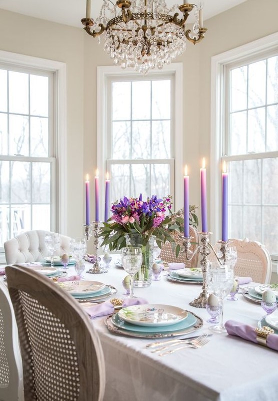 a refined colorful spring tablescape with a bright floral centerpiece, purple candles, printed plates and chargers