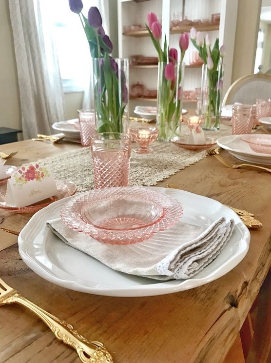 a vintage-inspired spring tablescape with pink glass, pink tulips in vases and a lace table runner