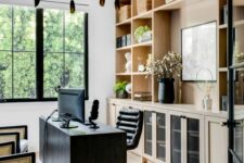 a beautiful and contrasting home office with light-stained cabinetry, a black desk and a chair, cane chairs and a black chandelier