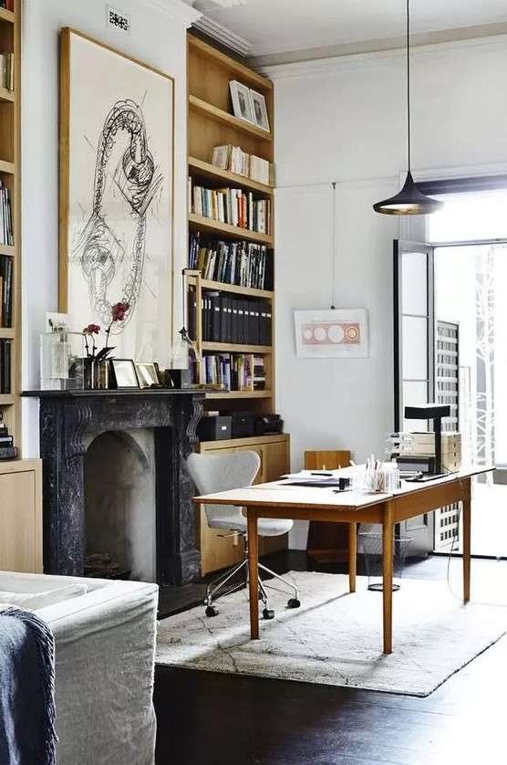a beautiful modern Victorian home office with built-in bookcases, a non-working fireplace, a simple and a neutral chair, a black pendant lamp