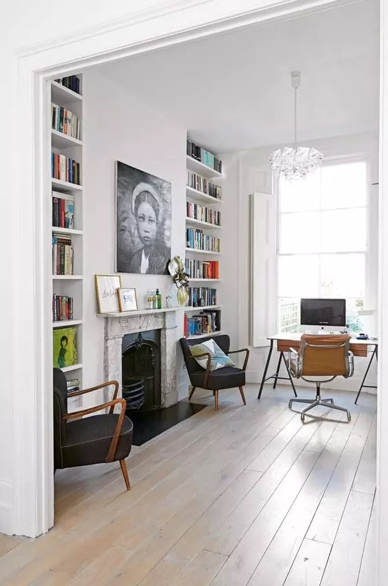 a beautiful modern home office in white, with built-in bookshelves, a fireplace with a marble surround, a stylish desk and black and beige chairs