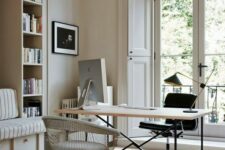 a beautiful neutral home office with built-in storage units and a daybed, a laconic desk, a black and a silver chair, an entrance to a balcony