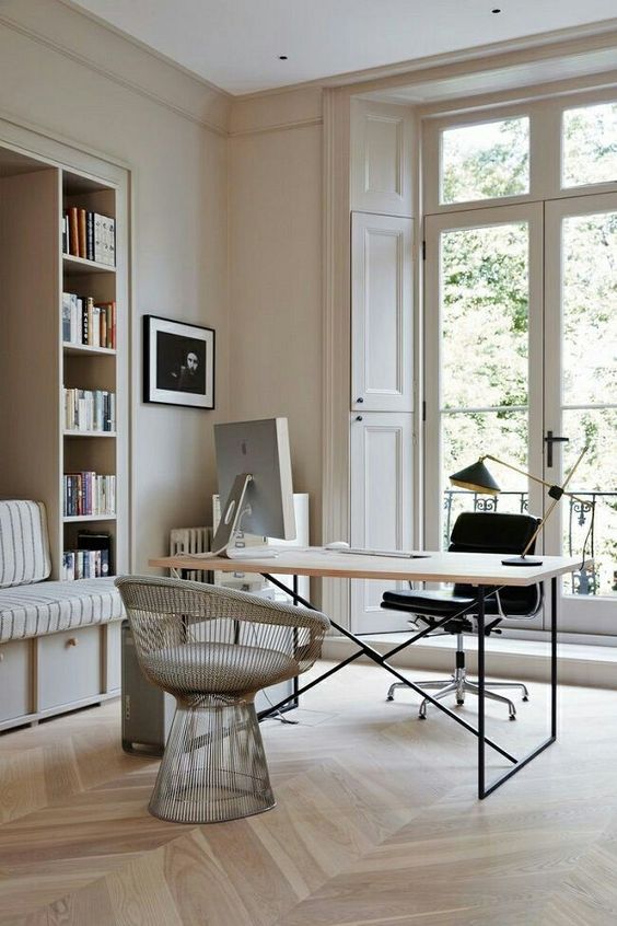 a beautiful neutral home office with built-in storage units and a daybed, a laconic desk, a black and a silver chair, an entrance to a balcony