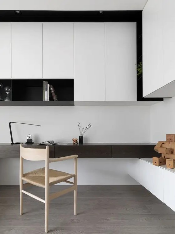 a bold minimalist home office in black and white, with sleek storage units and an open shelf, a built-in dark-stained desk and a woven chair