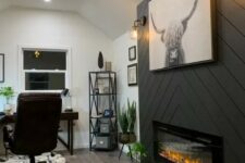 a farmhouse home office with a built-in fireplace clad with grey planked, a dark stained corner desk, a leather chair and potted plants