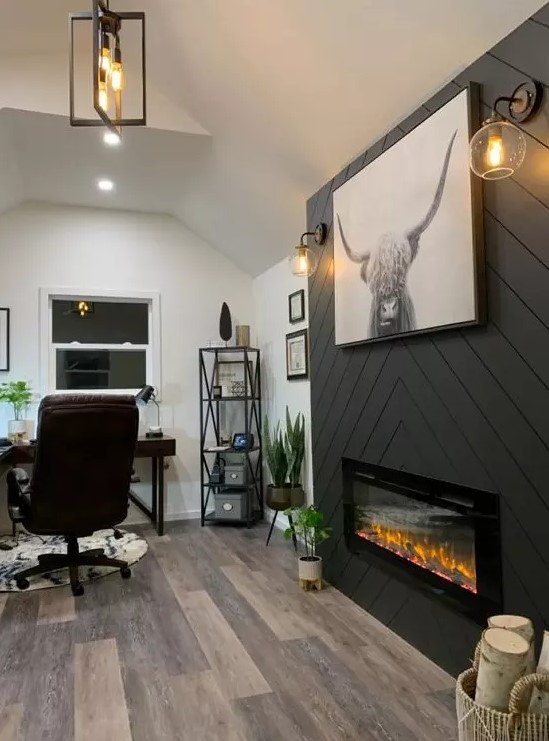 a farmhouse home office with a built-in fireplace clad with grey planked, a dark stained corner desk, a leather chair and potted plants
