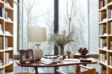 a gorgeous modern country home office with shelving units, a desk, a woven chair, a glazed wall for a lovely view and some wooden accessories